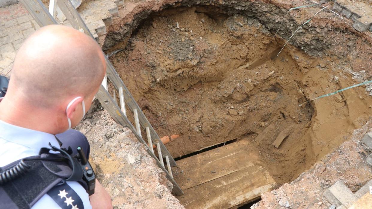 Ein Polizist schaut auf das Loch eines Tunnels, den Unbekannte zur Volksbank gegraben haben.