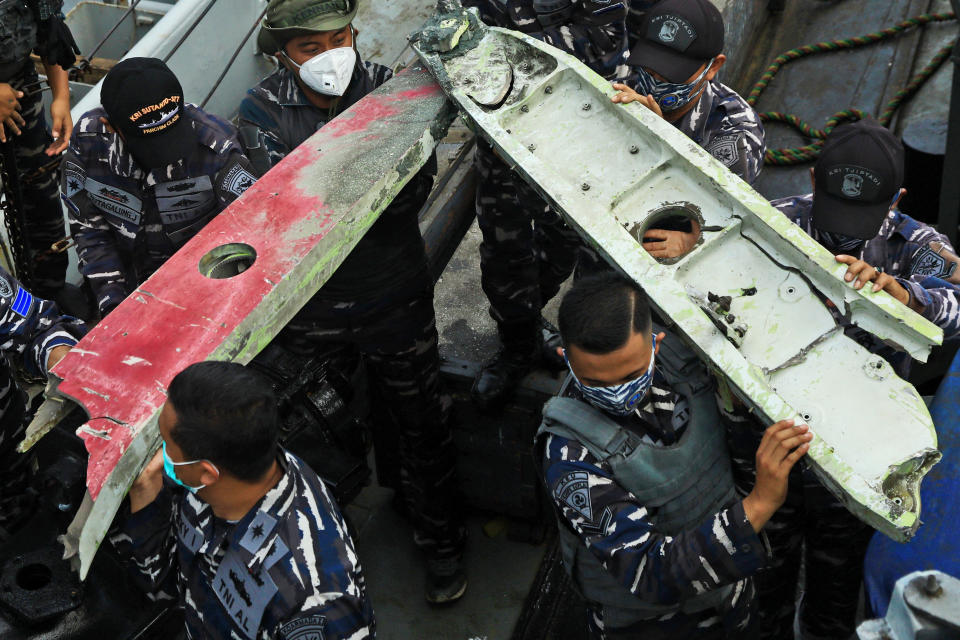 Indonesia navy sailors carry debris recovered from the waters off Java Island where a Sriwijaya Air passenger jet crashed on Saturday near Jakarta, Indonesia, Sunday, Jan. 10, 2021. Indonesian divers on Sunday located parts of the wreckage of the Boeing 737-500 at a depth of 23 meters (75 feet) in the Java Sea, a day after the aircraft with dozens of people onboard crashed shortly after takeoff from Jakarta. (AP Photo/Azwar Ipank)