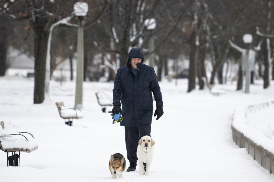 A person walks his dog along the Rideau River in the Sandy Hill neighborhood of Ottawa, on Friday, Dec. 23, 2022. Environment Canada has issued a winter storm warning for the region which is calling for flash freezing, icy and slippery surfaces, wind gusts and chills. (Spencer Colby /The Canadian Press via AP)