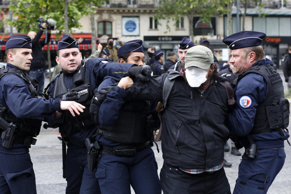 FILE - In this May 1, 2020 file photo, a man is arrested by police officers not wearing masks during a May Day demonstration, in Paris, during nationwide confinement measures to counter the Covid-19. From the U.S. president to the British prime minister's top aide and far beyond, leading officials around the world are refusing to wear masks or breaking confinement rules meant to protect their populations from the coronavirus and slow the pandemic. While some are punished when they're caught, or publicly repent, others shrug off the violations as if the rules don't apply to them. (AP Photo/Thibault Camus, File)