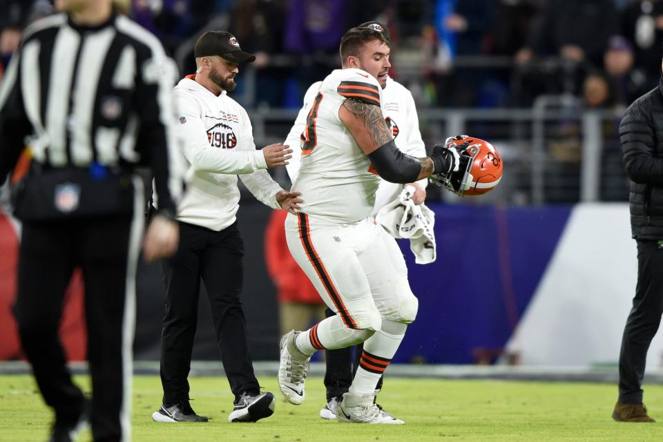 Cleveland Browns offensive tackle Jack Conklin, center, stumbles as he walks off the field with medical staff after a play against the Baltimore Ravens during the first half of an NFL football game, Sunday, Nov. 28, 2021, in Baltimore. (AP Photo/Gail Burton)