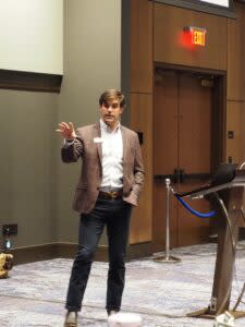  Donning a duck belt buckle, Austin Booth, director of the Game and Fish Commission, tells local officials about ongoing projects during a presentation on May 21, 2024. (Mary Hennigan/Arkansas Advocate)