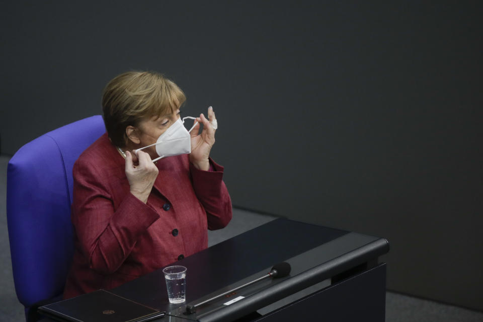 German Chancellor Angela Merkel adjusts her face mask as she arrives for a parliament session about a new law to battle the coronavirus pandemic at the Bundestag at the Reichstags building in Berlin, Germany, Friday, April 16, 2021. (AP Photo/Markus Schreiber)