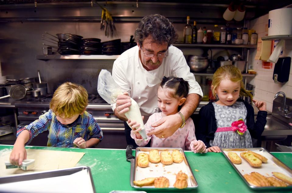 Chef Jean-Pierre Leverrier teaches his grandchildren Sebastian, 3, Isabella, 4, and Eva, 5, how to cut dough and fill profiteroles in his restaurant kitchen in November 2014.
