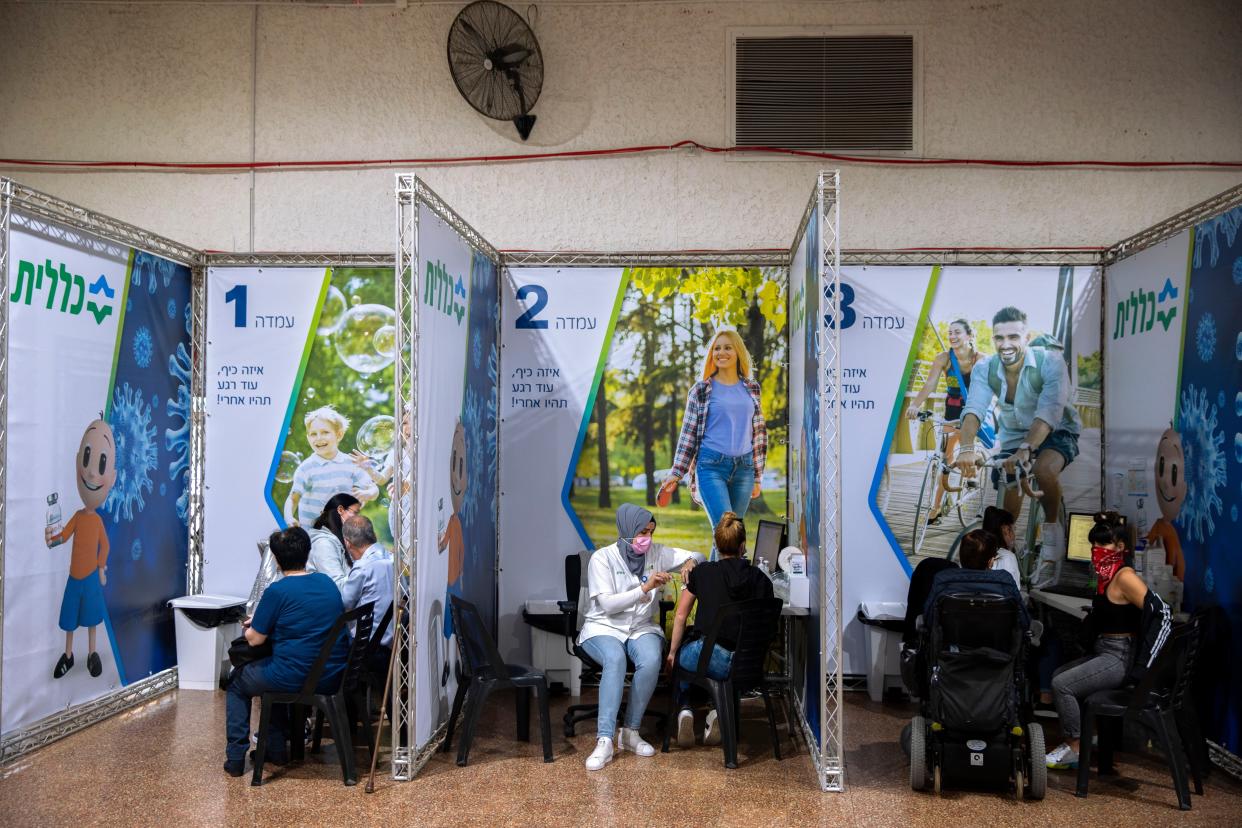 People receive coronavirus vaccines at a COVID-19 vaccination center in Ramat Gan, Israel, Sunday, Jan. 3, 2021.