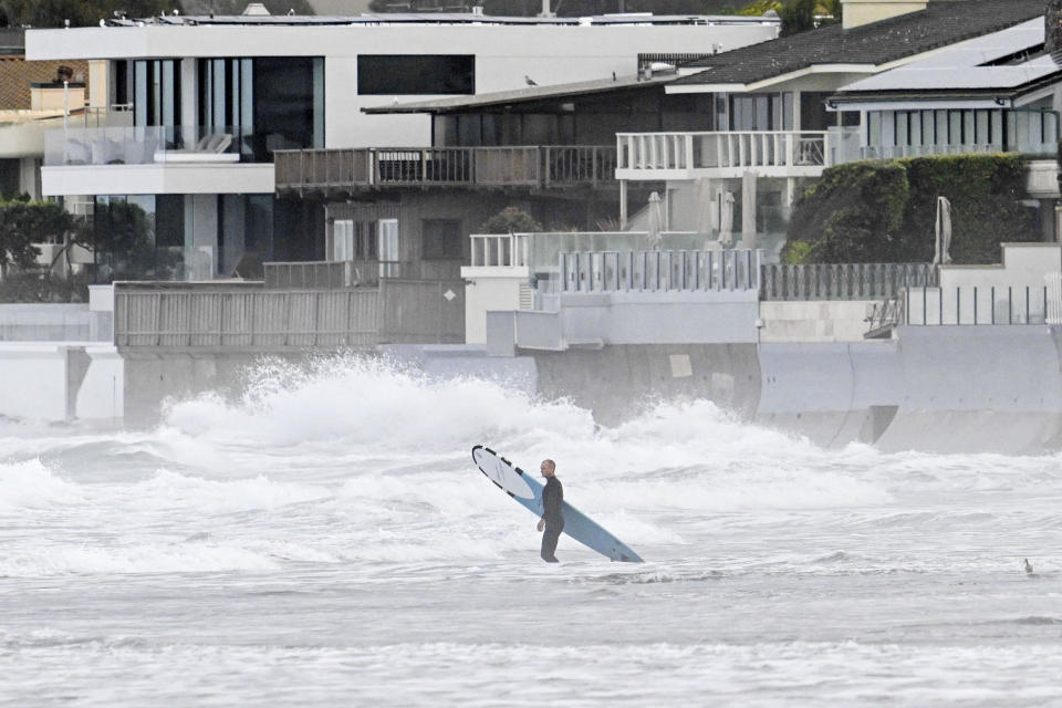 A surfer enters the water at La Jolla Shores Tuesday, Jan. 23, 2024, in La Jolla, Calif. California Gov. Gavin Newsom declared a state of emergency for San Diego County and Ventura County, which was also hit by heavy rains that caused flooding there in late December, stating that “I find that local authority is inadequate to cope with the magnitude of the damage caused by these winter storms.” (AP Photo/Denis Poroy)