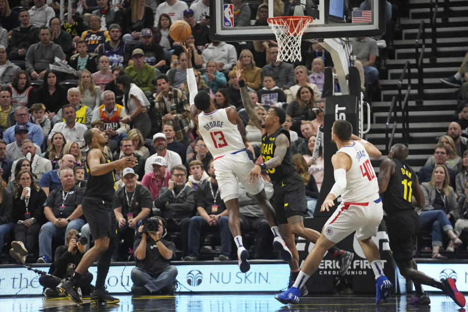 Los Angeles Clippers forward Paul George (13) shoots as Utah Jazz forward John Collins, center right, defends during the first half of an NBA basketball game Friday, Oct. 27, 2023, in Salt Lake City. (AP Photo/Rick Bowmer)