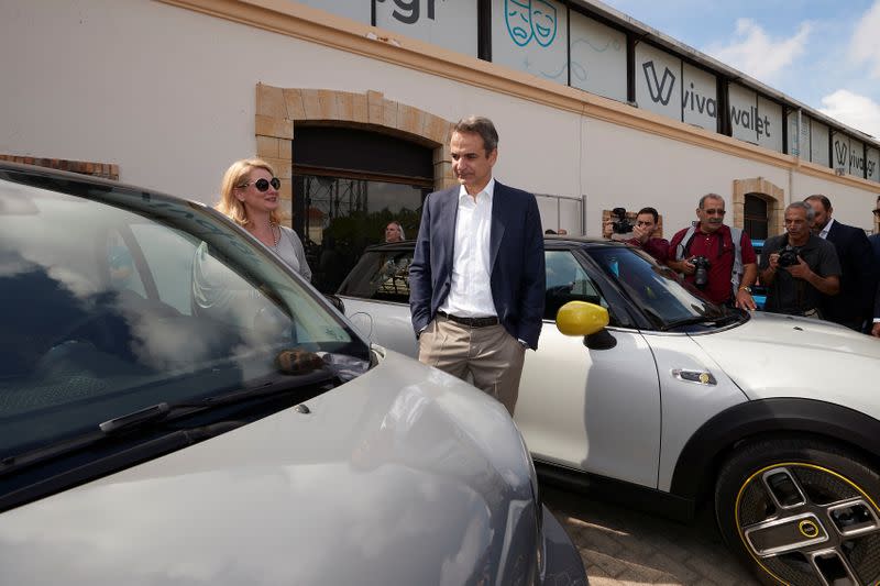 Greek Prime Minister Kyriakos Mitsotakis stands next to an electric car during an event about the country's low-carbon mobility plan, in Athens