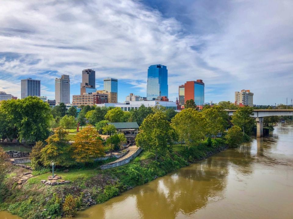 Little Rock Arkansas skyline near river and many trees.