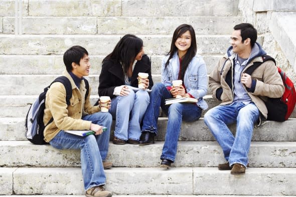 Four college students sitting on steps and smiling