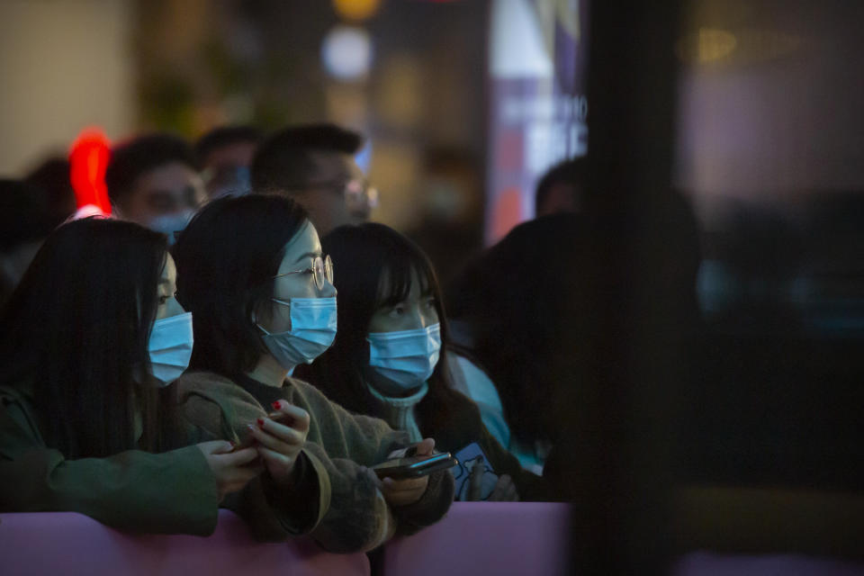 People wearing face masks to protect themselves against the coronavirus watch a livestreamer perform at a shopping mall in Beijing, Friday, Oct. 30, 2020. Chinese authorities are increasingly confident they have contained a COVID-19 outbreak in the country's far western region of Xinjiang. (AP Photo/Mark Schiefelbein)