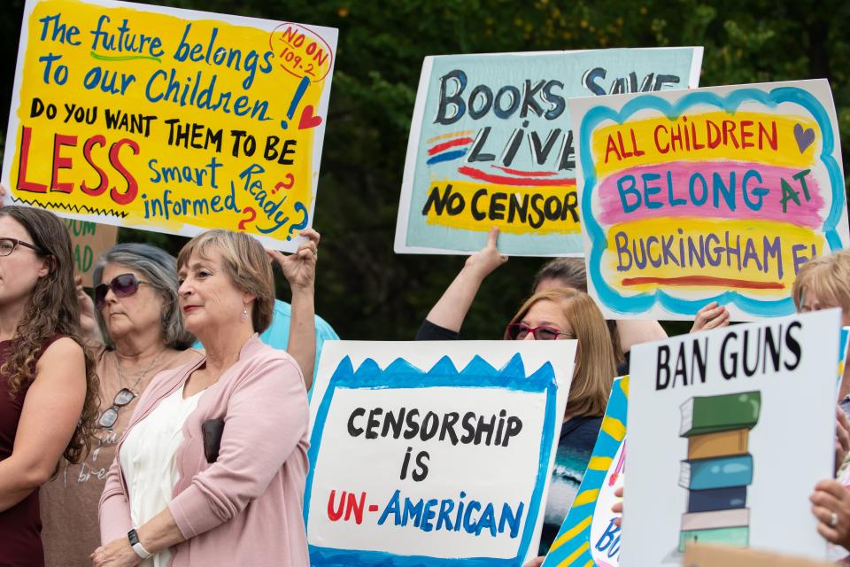 Opponents to a proposed library policy in the Central Bucks School District stood outside prior to a school board meeting on July 26, 2022, holding up signs comparing the policy to censorship and book banning.
