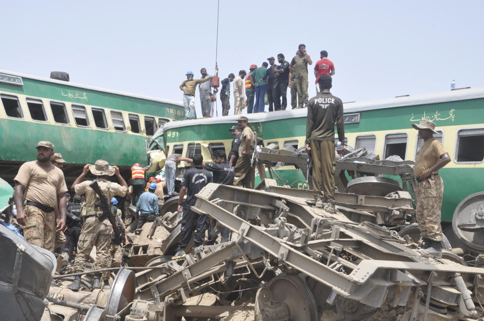 Pakistani officials and volunteers work at a train crash site in Rahim Yar Khan, Pakistan, Thursday, July 11, 2019. A passenger train rammed into a freight train in southern Pakistan on Thursday, killing many people and injuring others, an official said. (AP Photo/Waleed Saddique)