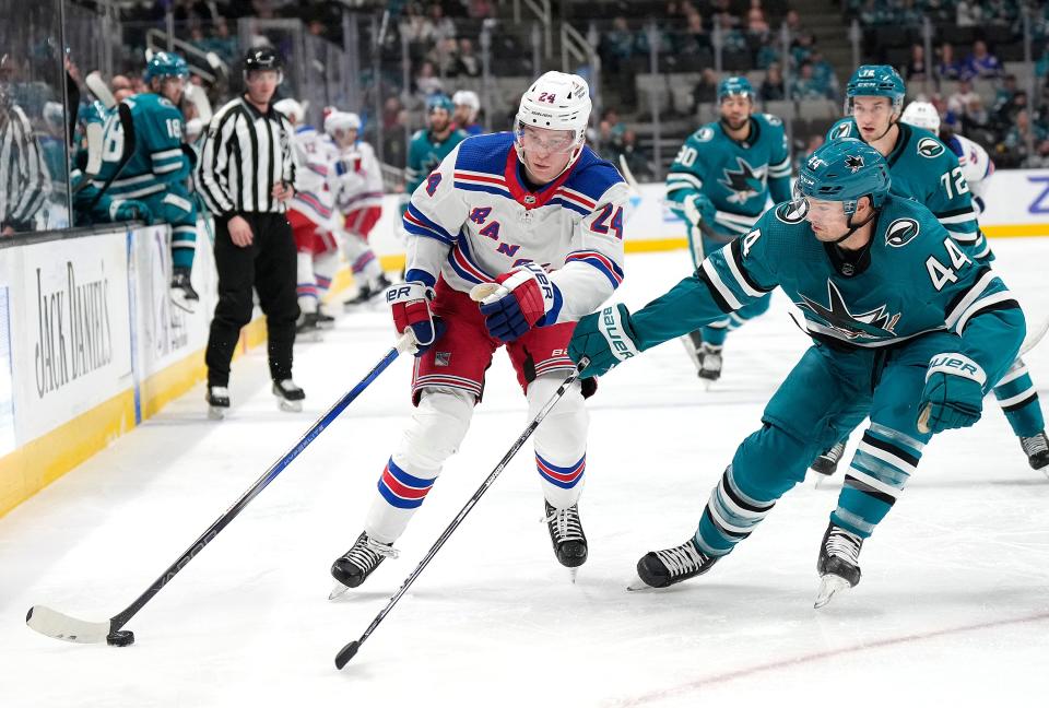 SAN JOSE, CALIFORNIA - JANUARY 23: Kaapo Kakko #24 of the New York Rangers skates up ice with the puck defended by Marc-Edouard Vlasic during the first period at SAP Center on January 23, 2024 in San Jose, California.