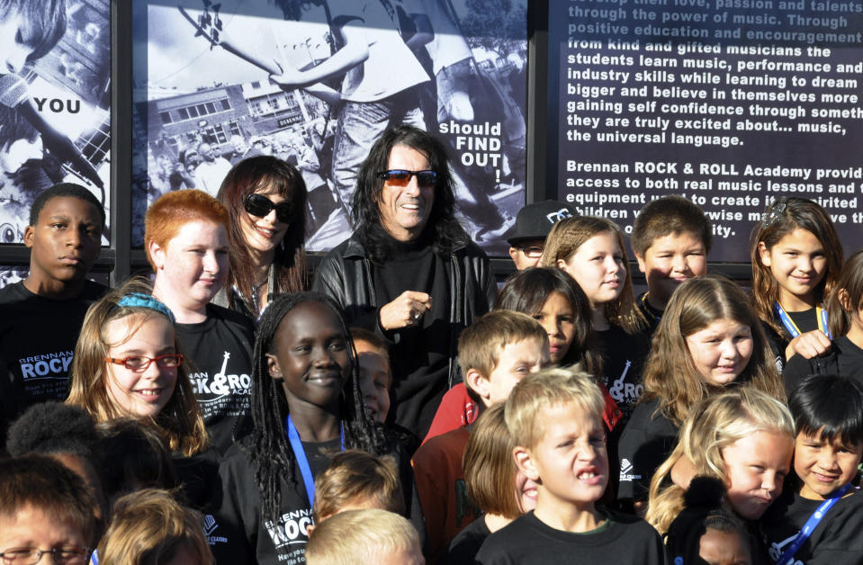 Heavy metal icon Alice Cooper, rear center right, and his wife, Sheryl, rear center left, pose with members of the Boys & Girls Clubs of the Sioux Empire, Wednesday, Oct. 10, 2012, in Sioux Falls, S.D. Cooper was in South Dakota to help his friend, Dollar Loan Center majority owner Chuck Brennan, open a 6,000-square-foot rock ëní roll academy that will be open exclusively to club members. (AP Photo/Dirk Lammers)