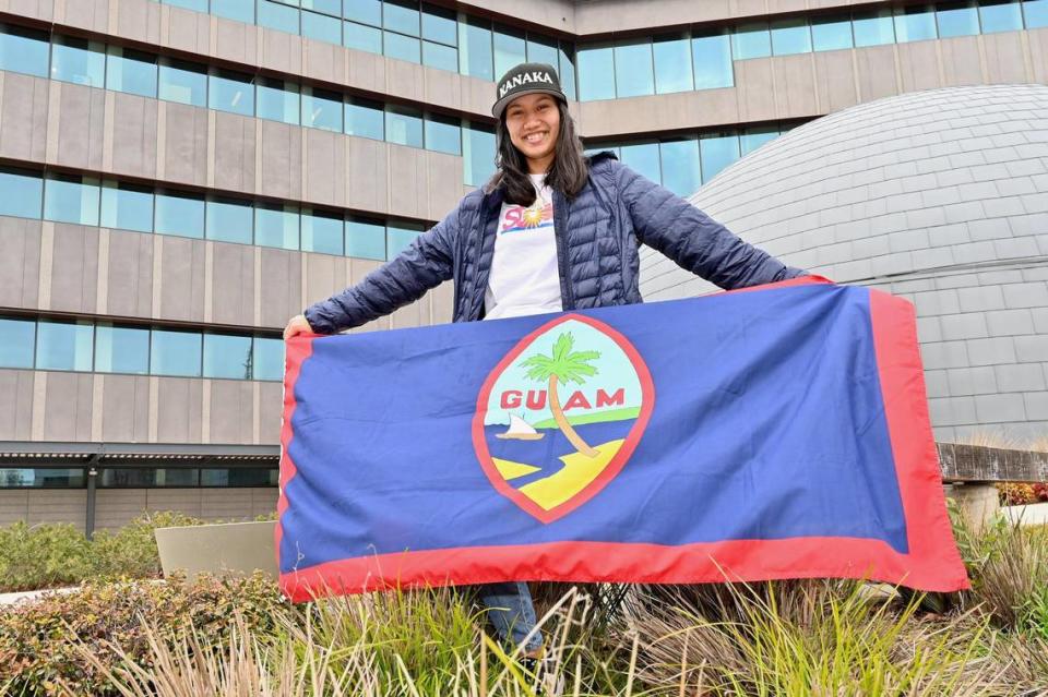 Maelani Gumataotao, a first-generation Pacific Islander student, holds a Guam flag in front of the Tschannen Science Complex at Sacramento State earlier this month.