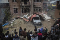 Kashmiri villagers gather near a house that was damaged during a gun battle between government forces and suspected rebels in Bijbehara, some 28 miles (45 kilometers) south of Srinagar, Indian controlled Kashmir, Sunday, April 11, 2021. (AP Photo/Mukhtar Khan)