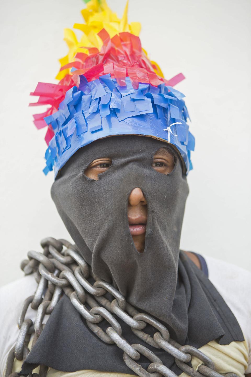 In this April 18, 2014 photo, a youth in a mask poses for a picture during a break while participating in "Los Encadenados," or The Chained Ones procession on Good Friday during Holy Week in Masatepe, Nicaragua. More than 900 people participated in the event this year, some to keep the tradition alive and others to repay a promise to God. (AP Photo/Esteban Felix)