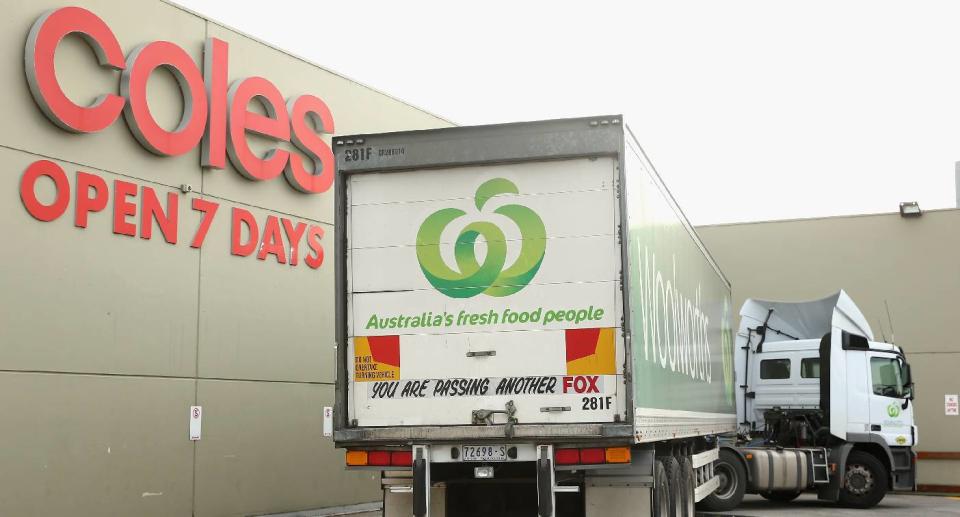 Woolworths truck parked in front of a Coles sign