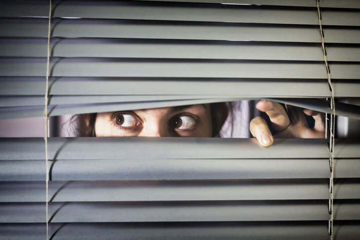 woman peeking through the window blinds