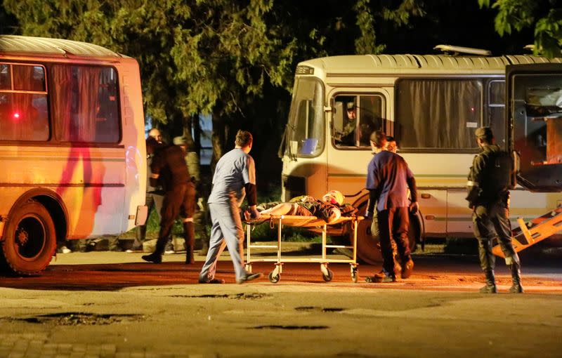 Un miembro herido de las fuerzas ucranianas de la planta siderúrgica Azovstal sitiada en Mariupol es transportado en una camilla fuera de un autobús, que llegó escoltado por militares prorrusos en Novoazovsk, Ucrania