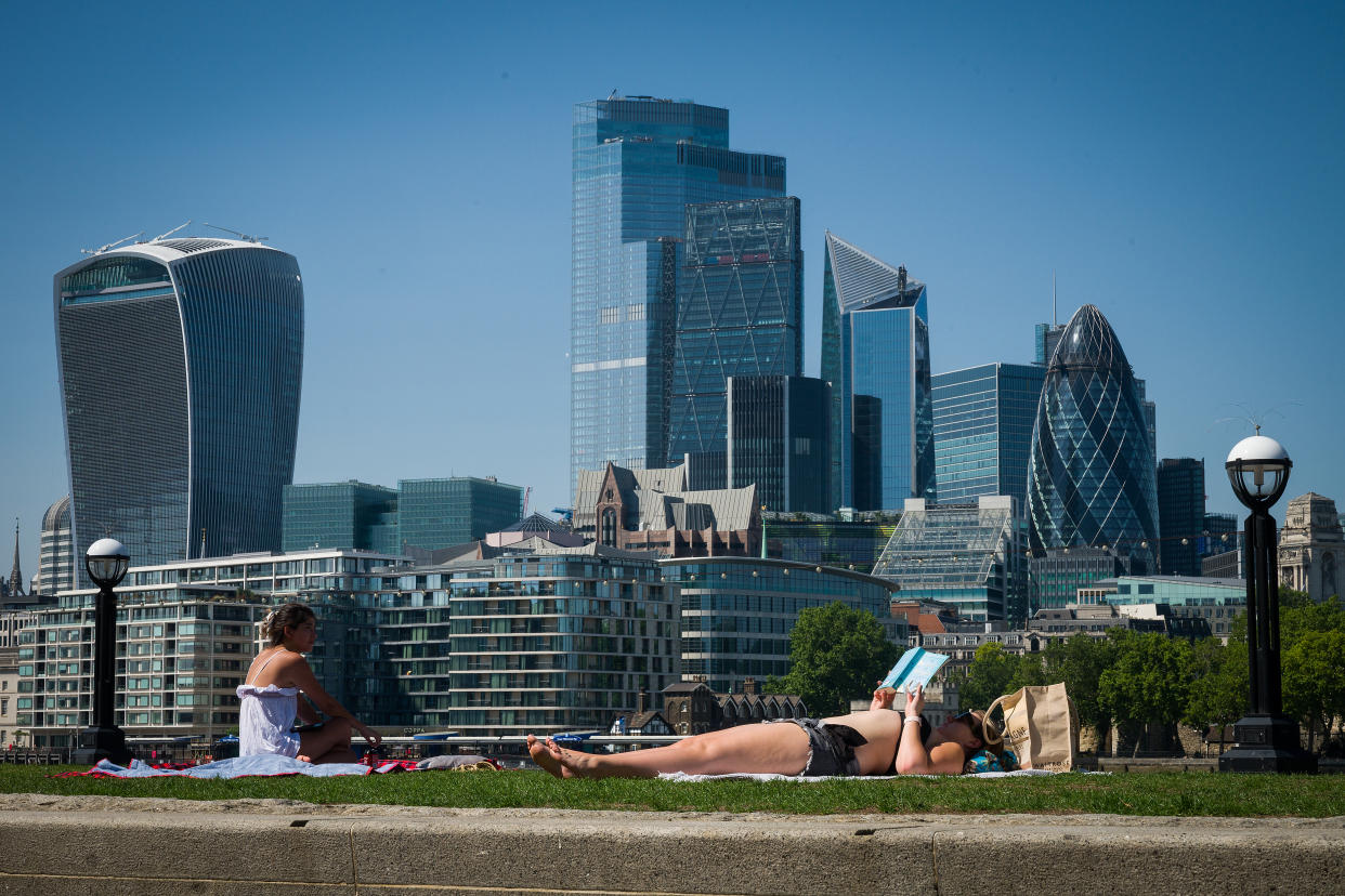 LONDON, UNITED KINGDOM - JUNE 24: People sunbathe on the park near Tower Bridge as the City of London is seen in the background on June 24, 2020 in London, United Kingdom. The UK is experiencing a summer heatwave, with temperatures in many parts of the country expected to rise above 30C and weather warnings in place for thunderstorms at the end of the week. (Photo by Leon Neal/Getty Images)