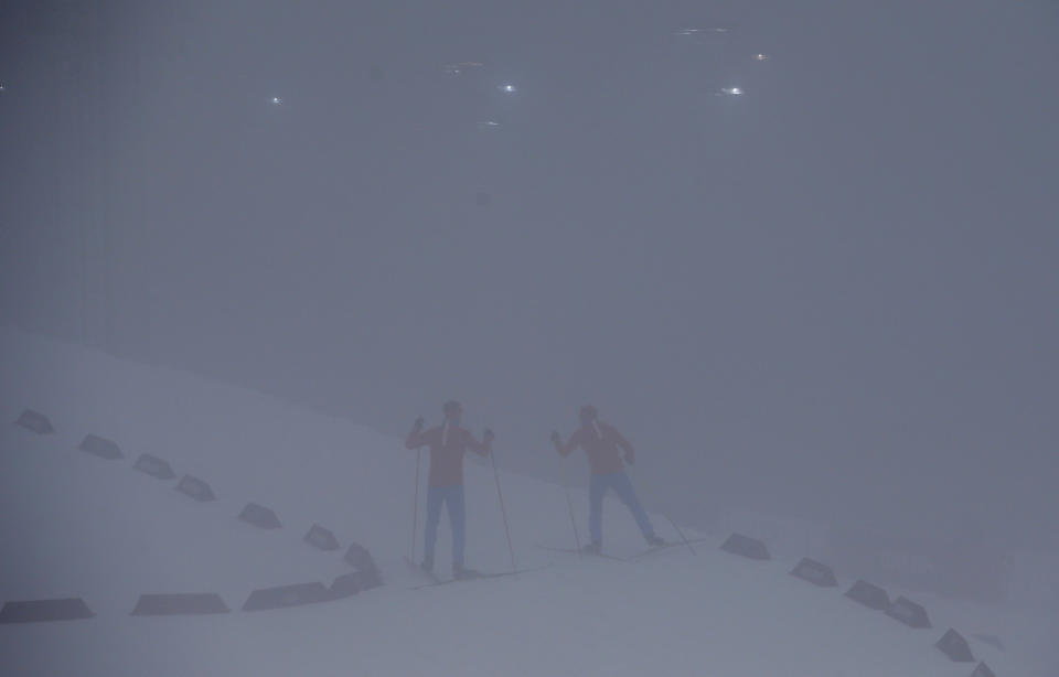 Unidentified athletes ski through the fog as the men's biathlon 15K mass start race has been postponed due to the lack of visibility at the 2014 Winter Olympics, Sunday, Feb. 16, 2014, in Krasnaya Polyana, Russia. (AP Photo/Gregorio Borgia)