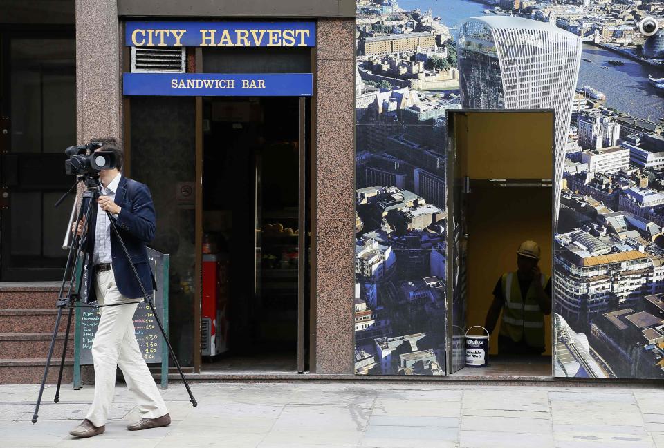 A journalist walks past a hoarding showing the Walkie Talkie tower in London