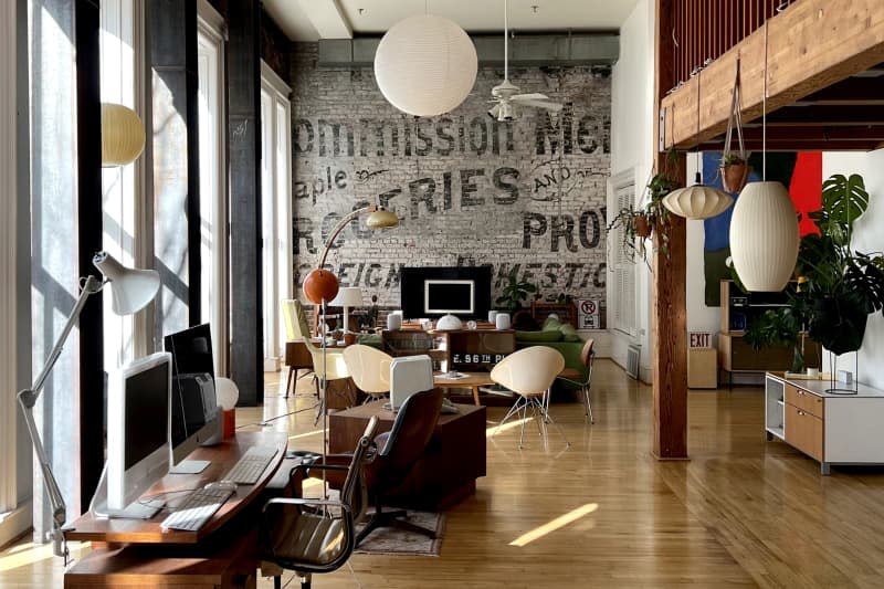 Work, living, and dining areas seen in loft with painted brick wall.