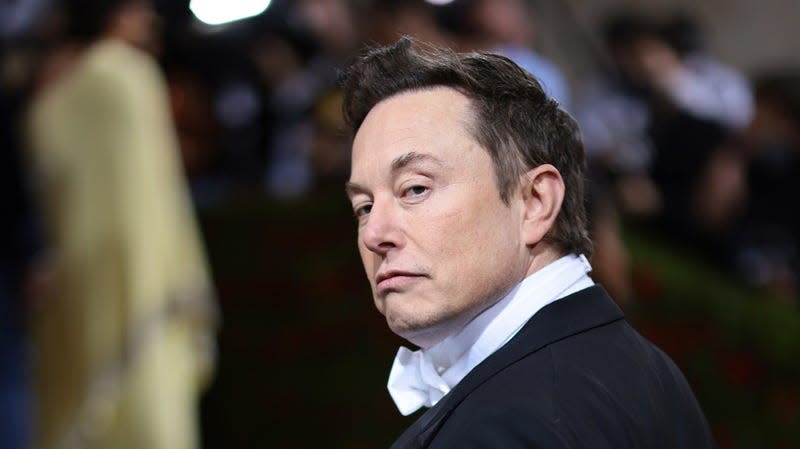 A photo of Elon Musk in a tux looking displeased is shown.