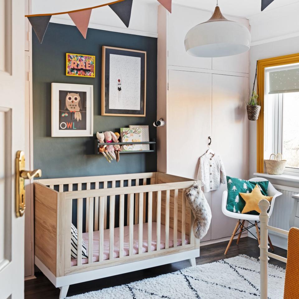 white cot in nursery with blue wall and prints