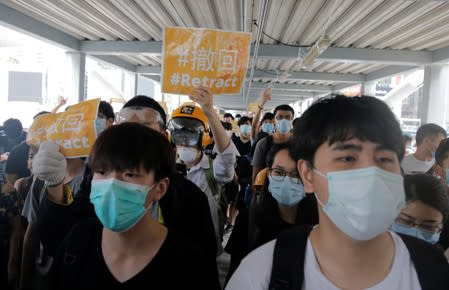 Protesters hold placards and shout slogans on a footbridge leading to the Legislative Council in Hong Kong