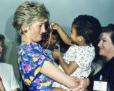 ARCHIVO . En esta fotografía del 24 de abril de 1991 la princesa Diana de Gran Bretaña, princesa de Gales, abraza y juega con un bebé VIH positivo en Faban Hostel, Sao Paulo, en Brasil. La princesa Diana, que era considerada tímida al saltar a la fama, se convirtió en una revolucionaria en sus años en la Casa de Windsor modernizando la monarquía como una institución más personal y cambiando la forma en la que la familia real se relacionaba con la gente. (Foto AP/Dave Caulkin, archivo)