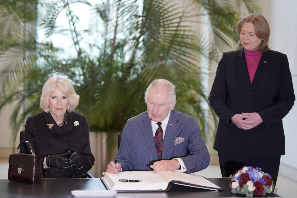 Britain's King Charles III, with Camilla, the Queen Consort, signs the guest book at the Bundestag, Germany's Parliament, as Bundestag President Baerbel Bas, right, watches, in Berlin, Thursday, March 30, 2023. King Charles III arrived Wednesday for a three-day official visit to Germany. (AP Photo/Markus Schreiber, Pool)
