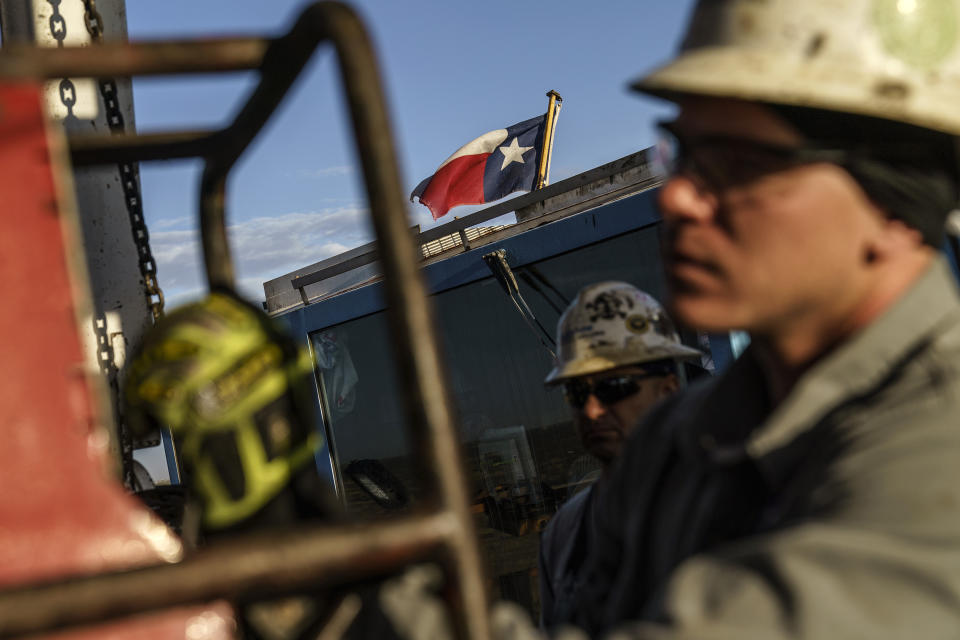 The Texas state flag flies above workers at Latshaw oil drilling rig #43 in the Permian Basin in Odessa, Texas, Wednesday, Oct. 13, 2021. More than 5,000 new well-drilling permits were issued in the Texas portion of the Permian in 2021, as demand for fossil fuels rebounded after a COVID-era slump in demand. Numbers from the first quarter of 2022 show the industry on pace to eclipse that figure. (AP Photo/David Goldman)