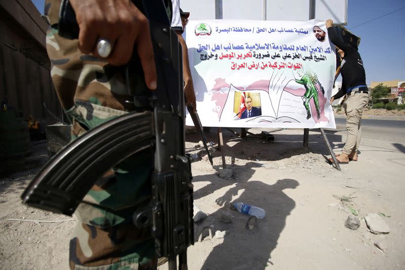 FILE PHOTO: Members of Shi'ite group Asaib Ahl al-Haq put banners in the street against Turkey's military presence in Iraq, in Basra
