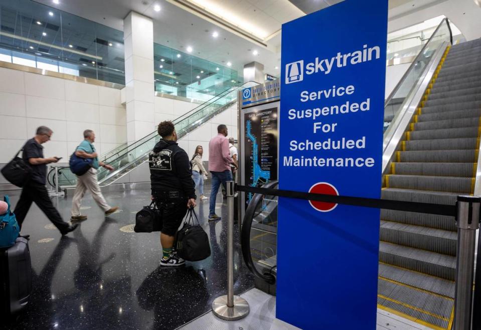 People with their luggage walk past a closed entrance to the Skytrain on Concourse D at Miami International Airport, Wednesday, Sept. 27, 2023. The Skytrain is down indefinitely and a courtesy shuttle is the only option passengers have besides walking to get from one end of the terminal to the other.