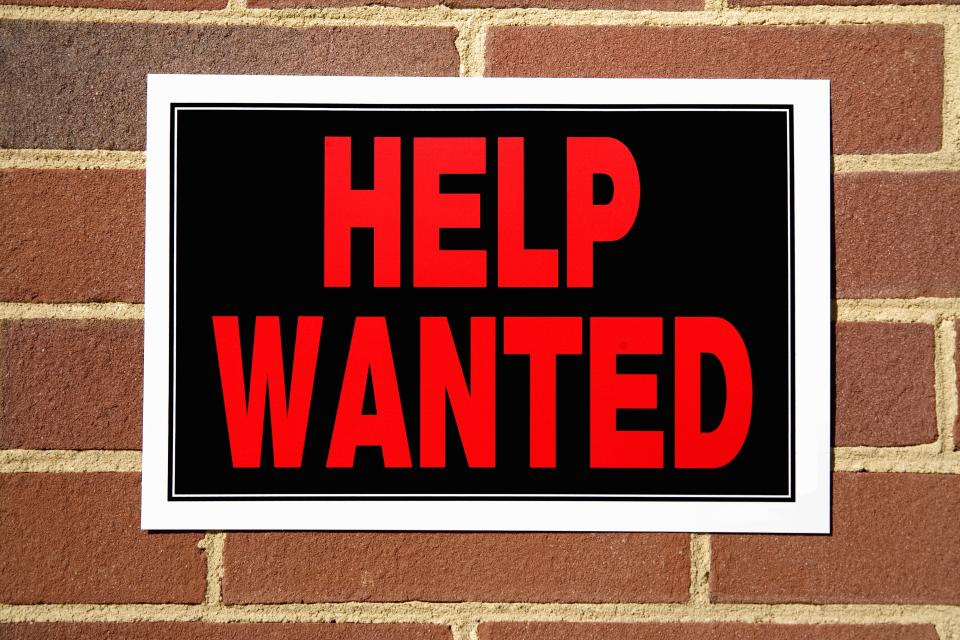 A "Help Wanted" sign on a brick wall