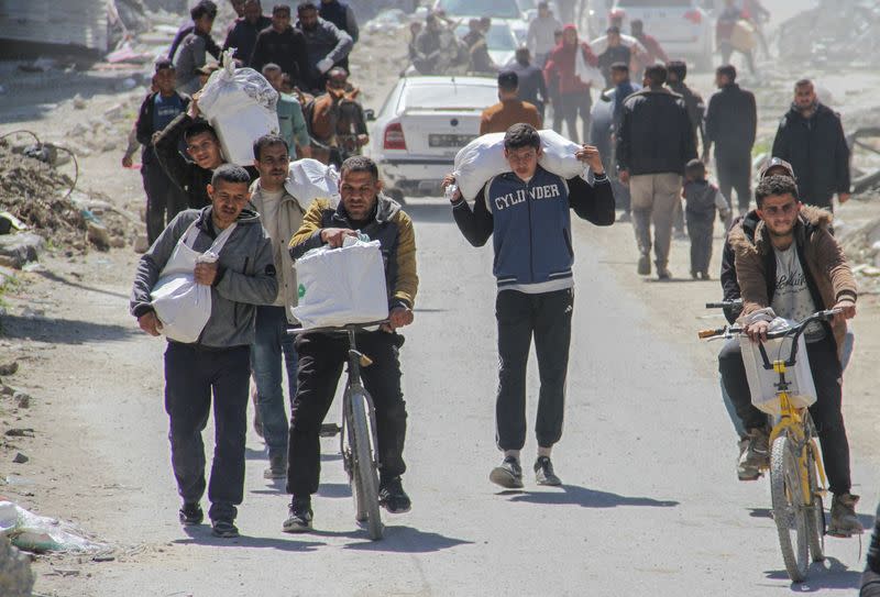 Palestinians carry aid unloaded from a truck, amid the ongoing conflict between Israel and Hamas, in Gaza City