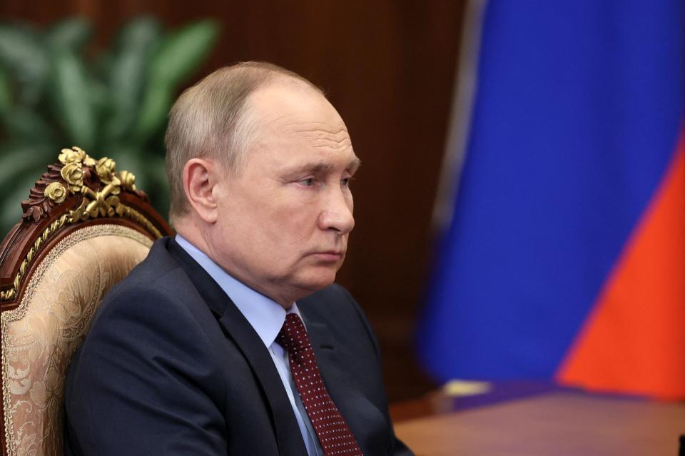 President Vladimir Putin on a padded gilt chair, looking downcast.