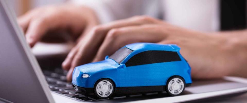 Close-up Of A Small Blue Car On Laptop Keypad