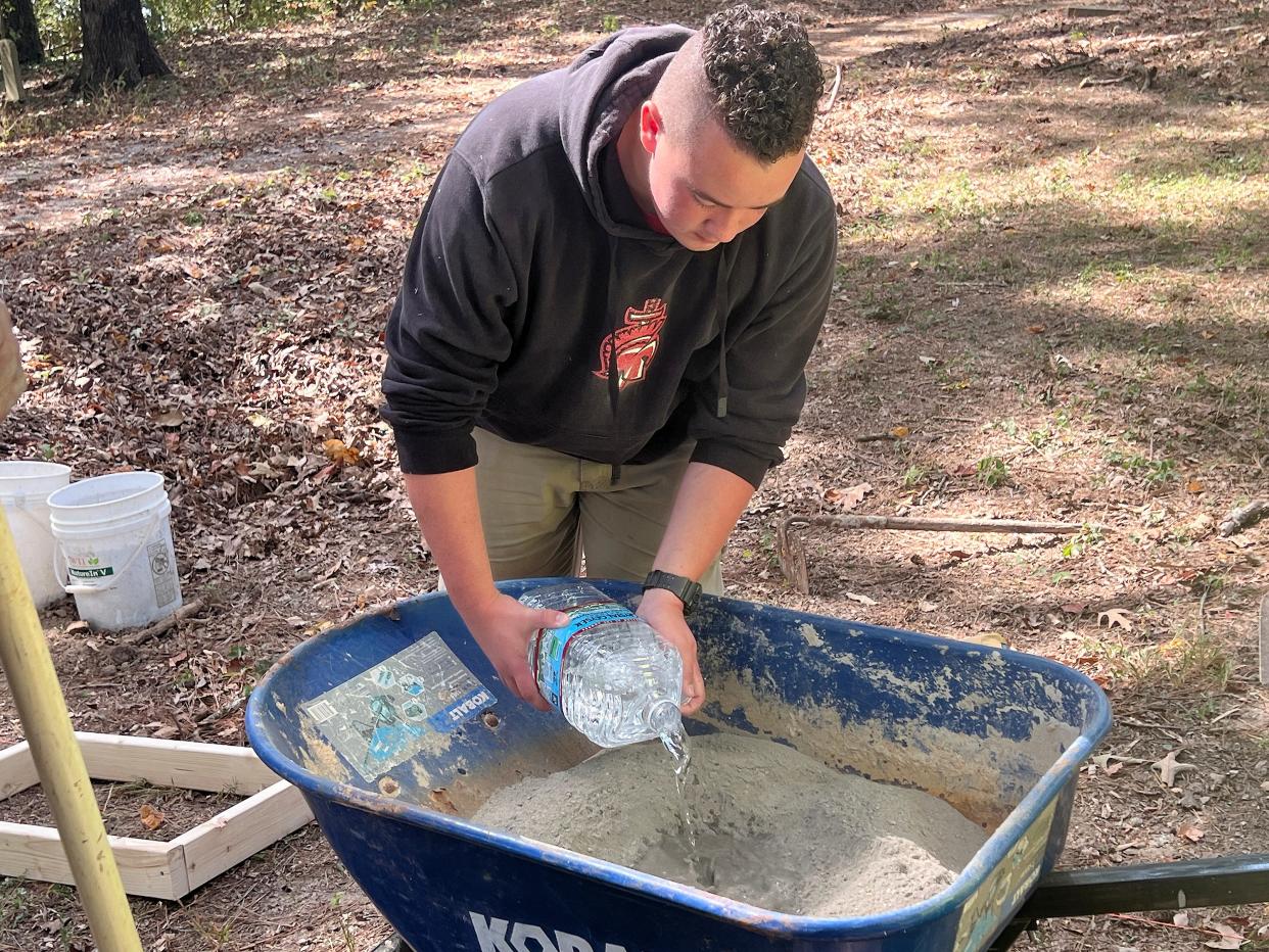 Noah Meredith mixes concrete at Southern Hills Cemetery in Gadsden. As his Eagle Scout project, Meredith is constructing 100 cement bases for headstones to be mounted at the historic Black cemetery.