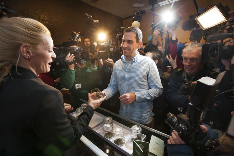 Iraq war veteran Sean Azzariti of Boston examines his marijuana selection as the first person to purchase the drug legally at the 3D Cannabis Center from owner Toni Fox (L) in Denver on January 1, 2014. File Photo by Gary C. Caskey/UPI