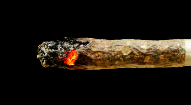 up close photo of a marijuana joint smoldering against a pitch black background