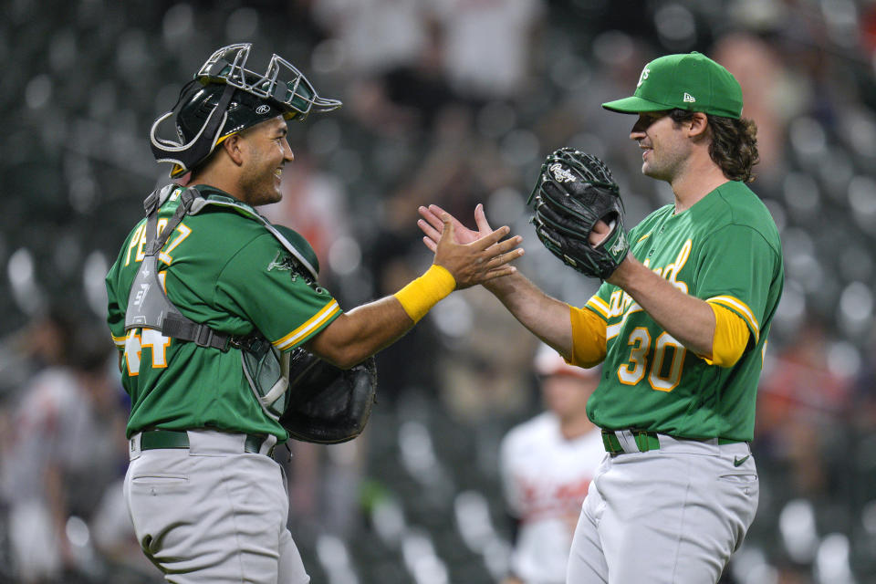 Oakland Athletics catcher Carlos Perez (44) and relief pitcher Chad Smith (30) celebrate the team's win over the Baltimore Orioles in a baseball game at Oriole Park at Camden Yards, Wednesday, April 12, 2023, in Baltimore. The Athletics won 8-4. (AP Photo/Jess Rapfogel)