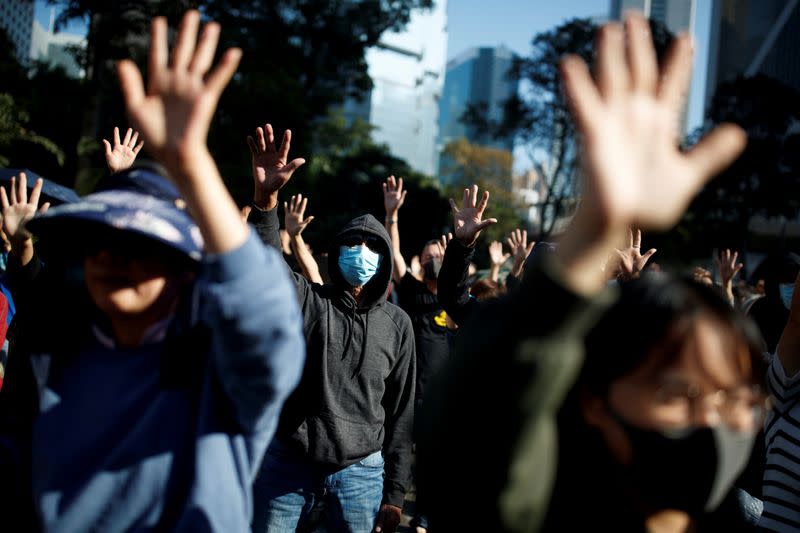 FILE PHOTO: People raise their hands as they sing the protest anthem "Glory to Hong Kong" during an anti-government protest in the Central district of Hong Kong