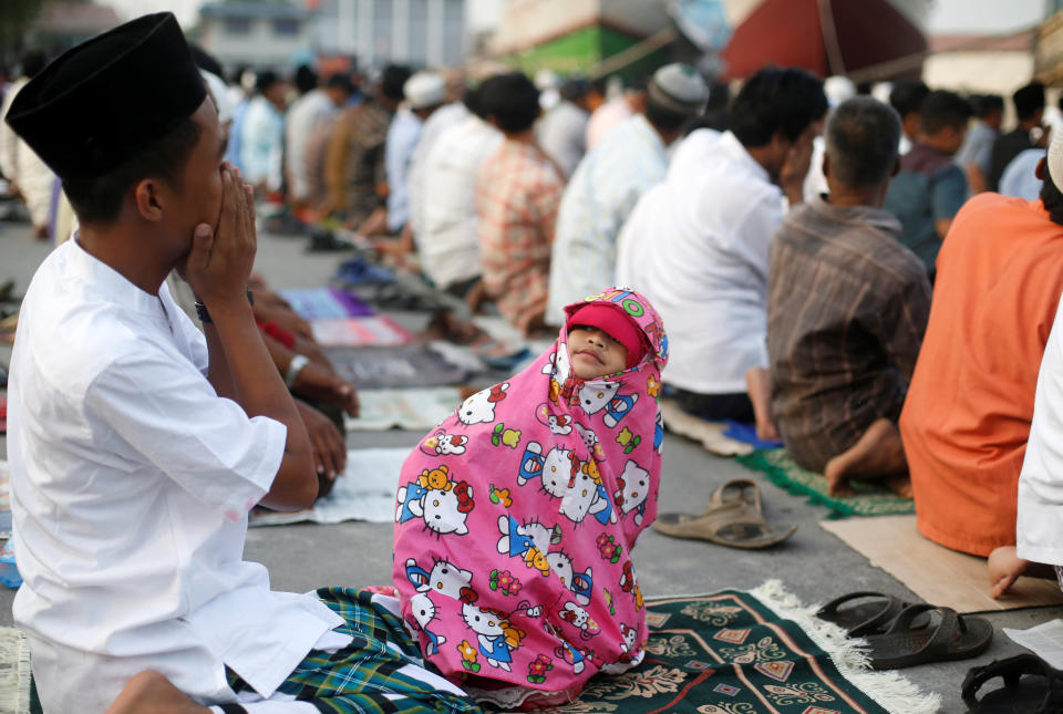 <p>A child looks at her father during prayers for the Muslim holiday of Eid Al-Adha at Sunda Kelapa port in Jakarta, Indonesia, Sept. 1, 2017. (Photo: Beawiharta/Reuters) </p>