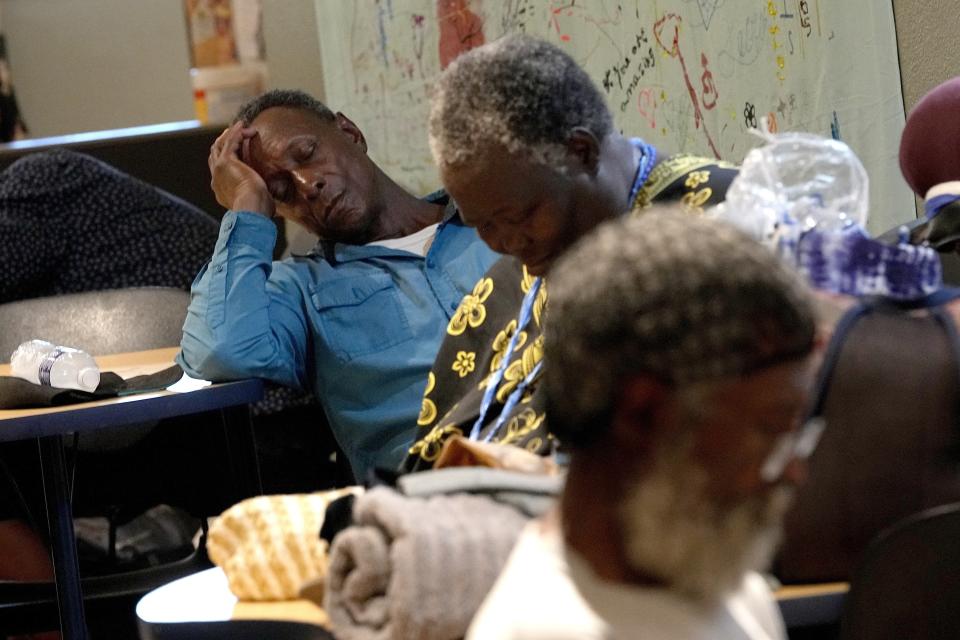 FILE - People, who are homeless watch a movie, hydrate and rest inside the Justa Center, a day cooling center for homeless people 55 years and older, July 14, 2023, in downtown Phoenix. Homeless people are among the people most likely to die in the extreme heat in metro Phoenix. (AP Photo/Matt York, File)