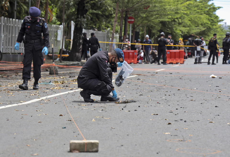 Members of police bomb squad search the area around the site of Sunday's suicide bomb attack at the Sacred Heart of Jesus Cathedral for evidence, in Makassar, South Sulawesi, Indonesia, Monday, March 29, 2021. Two attackers believed to be members of a militant network that pledged allegiance to the Islamic State group blew themselves up outside the packed Roman Catholic cathedral during a Palm Sunday Mass on Indonesia's Sulawesi island, wounding a number of people, police said. (AP Photo/Yusuf Wahil)