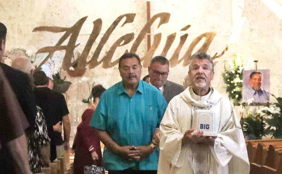 The Rev. Phil Egitto carries the urn of Big John's ashes Saturday morning during a memorial service at Our Lady of Lourdes Catholic Church in Daytona Beach. The longtime area businessman, politician and radio personality died May 15.